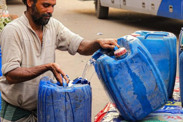 Man filling blue jerry cans with water