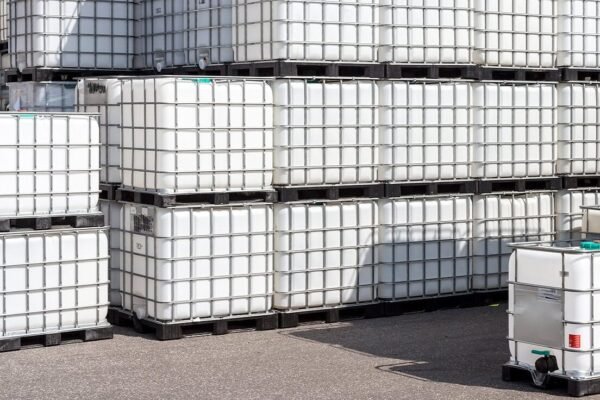 Rows of white IBC totes stacked in a yard