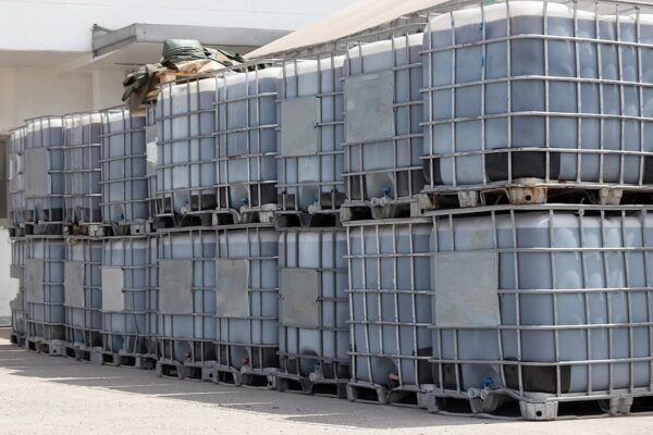 Stacked IBC totes on pallets outside a warehouse