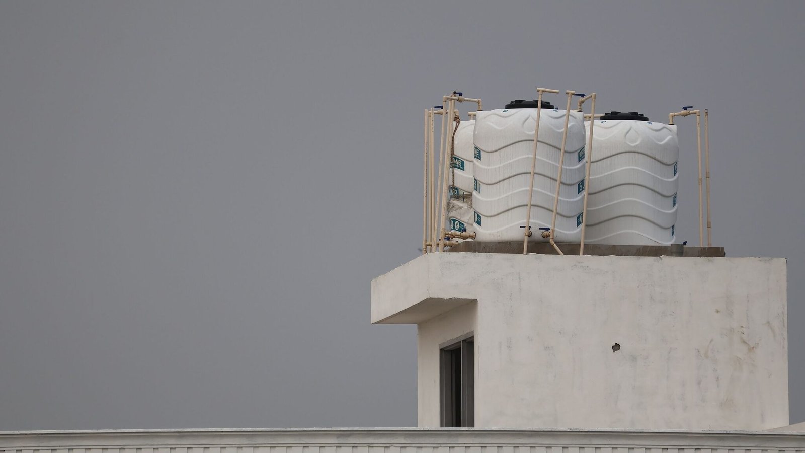 Two white water tanks on a rooftop